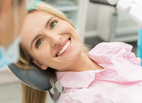 Woman smiling in dental chair during examination at family dentistry office.