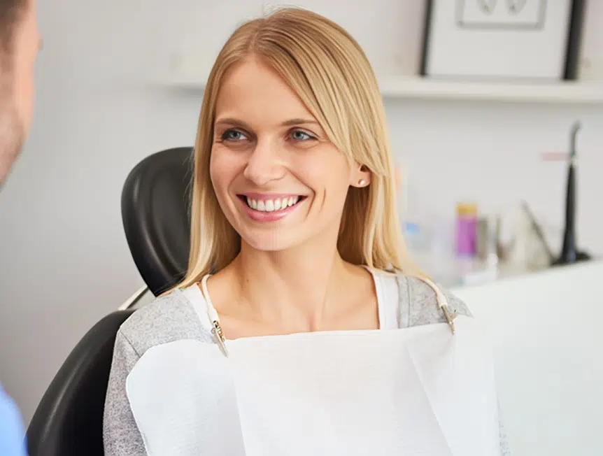 Smiling female dental professional in office setting with shelves in background
