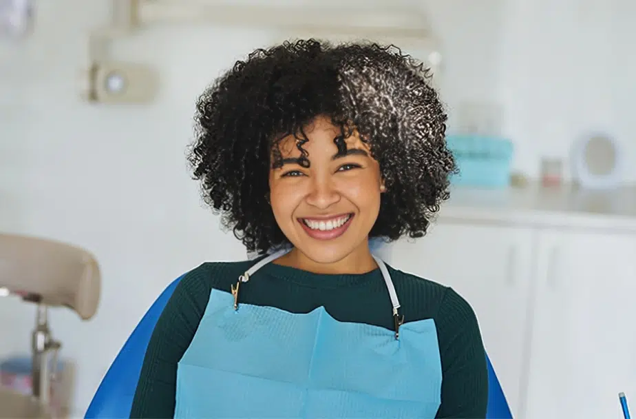 Smiling dental professional wearing blue apron in modern dentistry office setting.